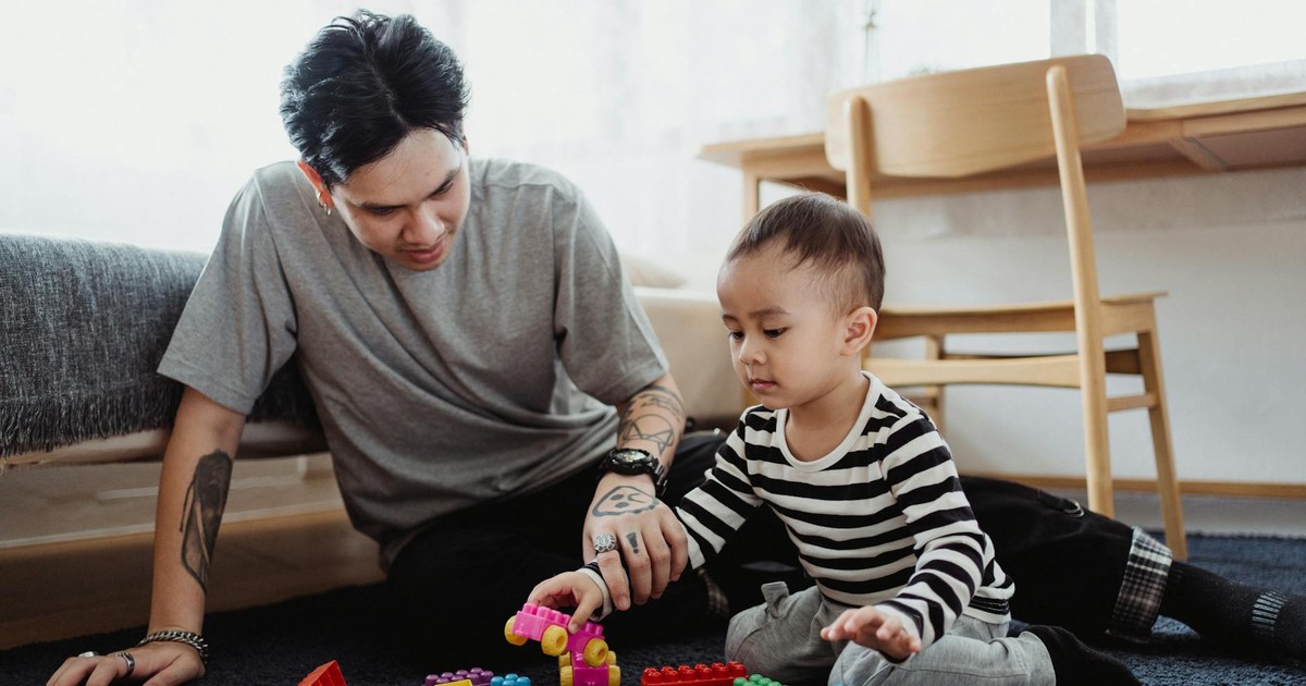 A father and son playing with colorful building blocks in a cozy indoor setting.