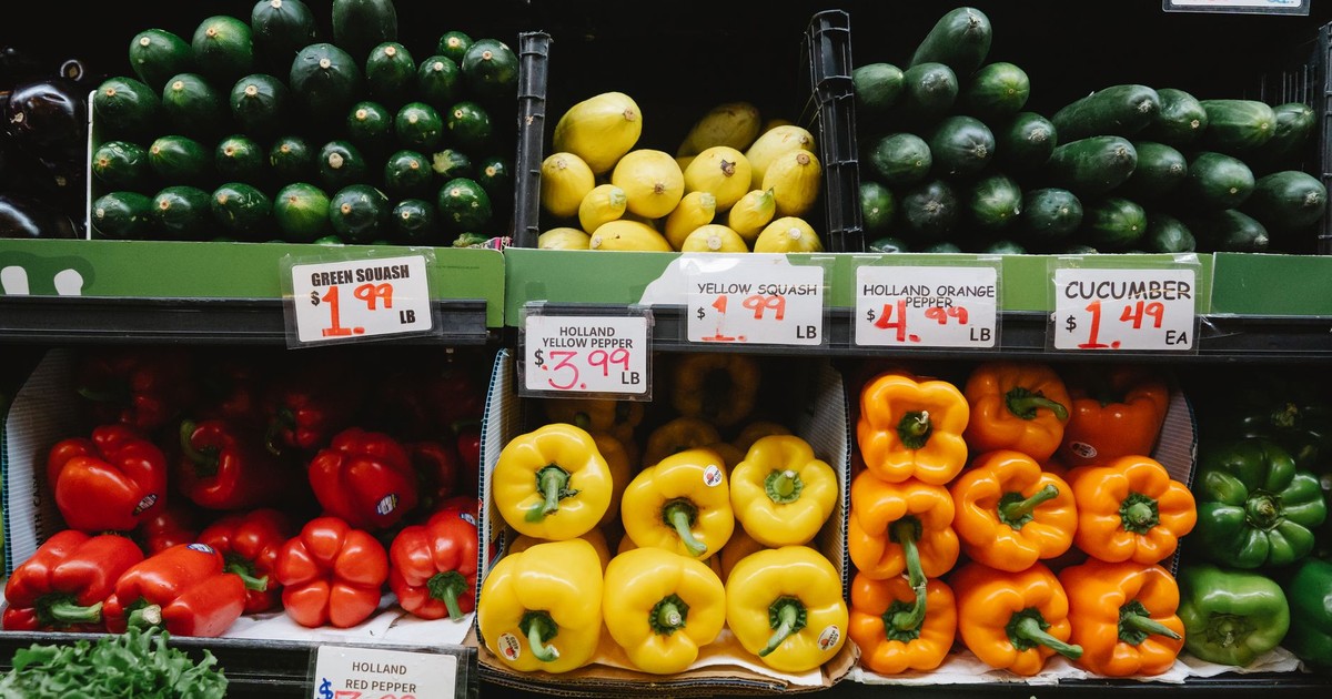 Colorful assortment of fresh vegetables at a supermarket display, highlighting peppers, squash, and cucumbers.
