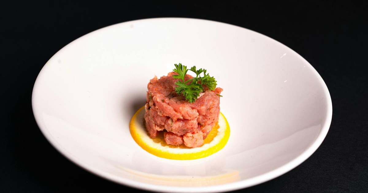 Delicious steak tartare served on a lemon slice in a minimalist setting.