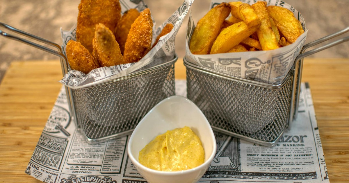 Delicious crispy chicken tenders served with fries and dipping sauce in a restaurant setting.