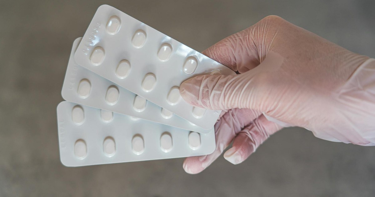 Gloved hand holding medication blister packs, representing healthcare and treatment.