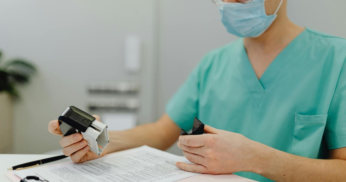 Healthcare worker in scrubs reviewing patient files with a stamp and clipboard.