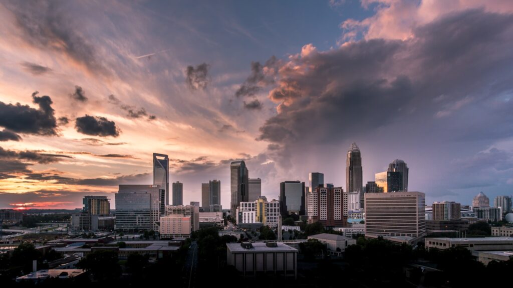 The Charlotte, North Carolina skyline under a dramatic sunset sky with pink and gray clouds.