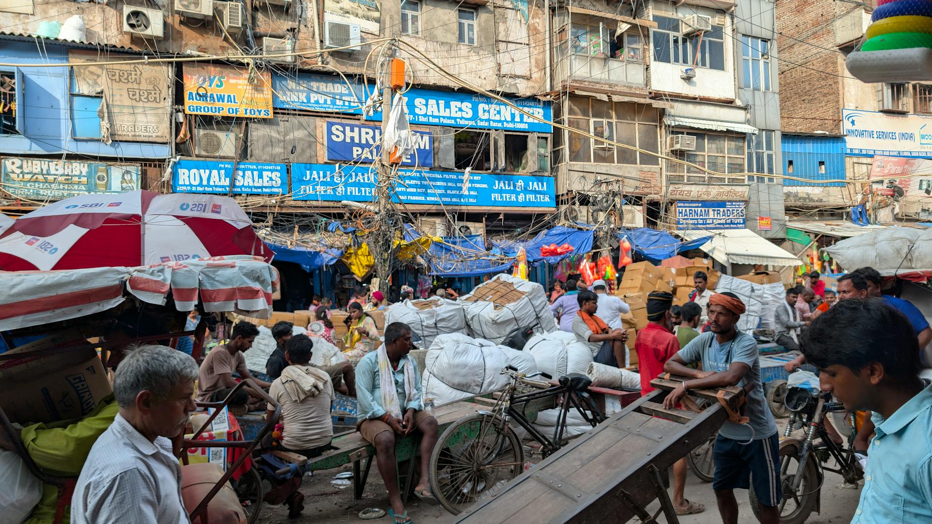 A vibrant and bustling street market in Old Delhi, India, with numerous vendors and shoppers.