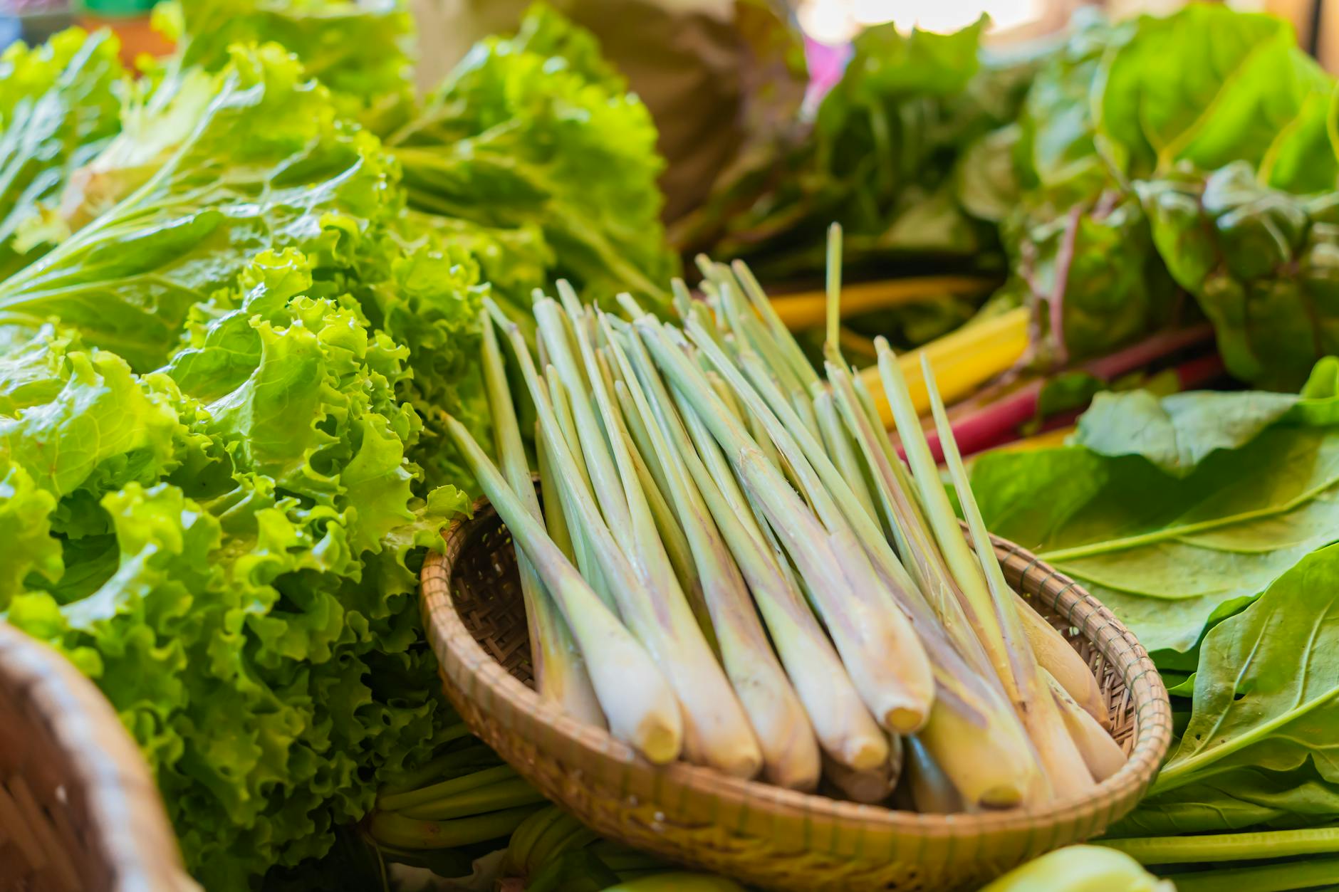 Close-up of fresh lemongrass and leafy vegetables on display at a vibrant local market.