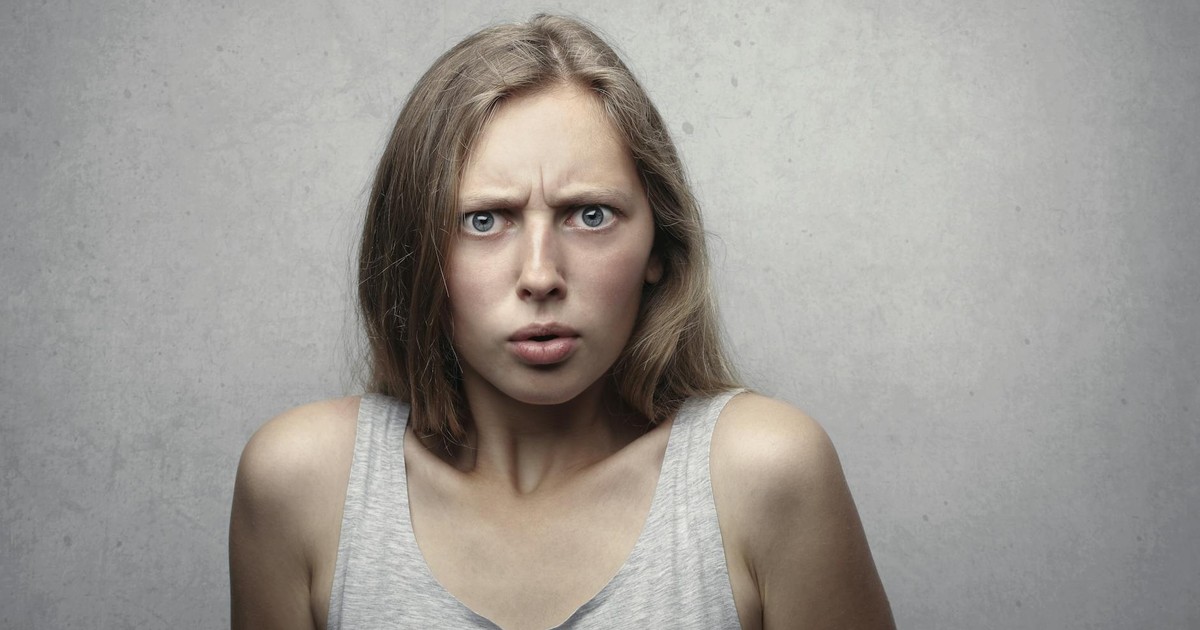 Close-up portrait of a pensive woman with a confused facial expression indoors.