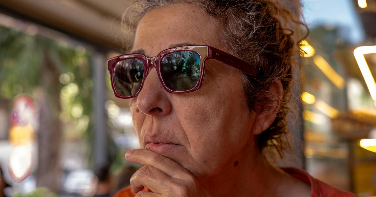 A thoughtful senior woman with sunglasses ponders outdoors, showcasing her profile in warm lighting.