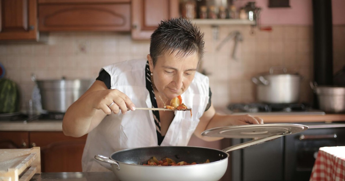 A woman savoring the aroma of a freshly cooked dish in a cozy kitchen setting.