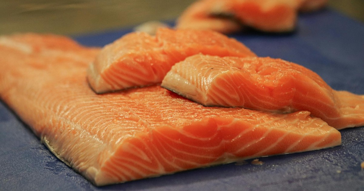 Close-up of fresh salmon fillets on a blue cutting board, ready for cooking.