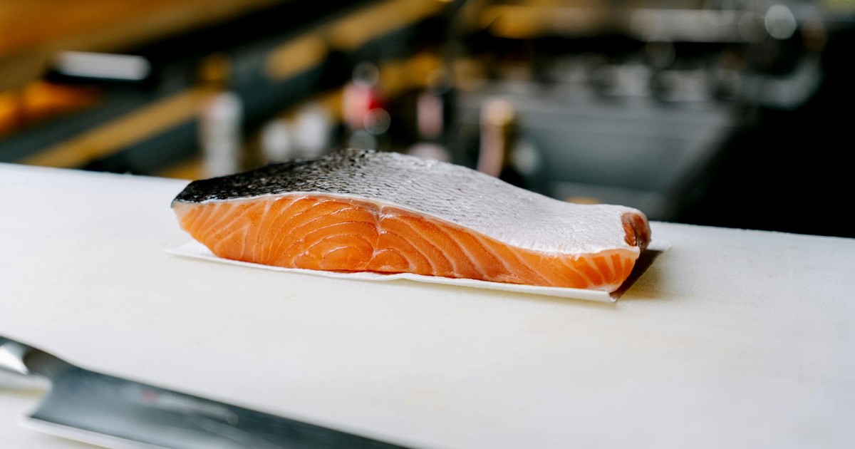 Close-up of a fresh salmon slice on a cutting board in a professional kitchen.