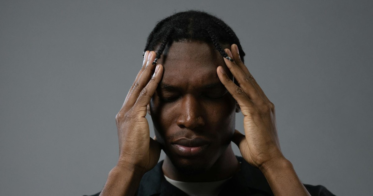 A contemplative black man with braided hair in a deep and emotional portrait.