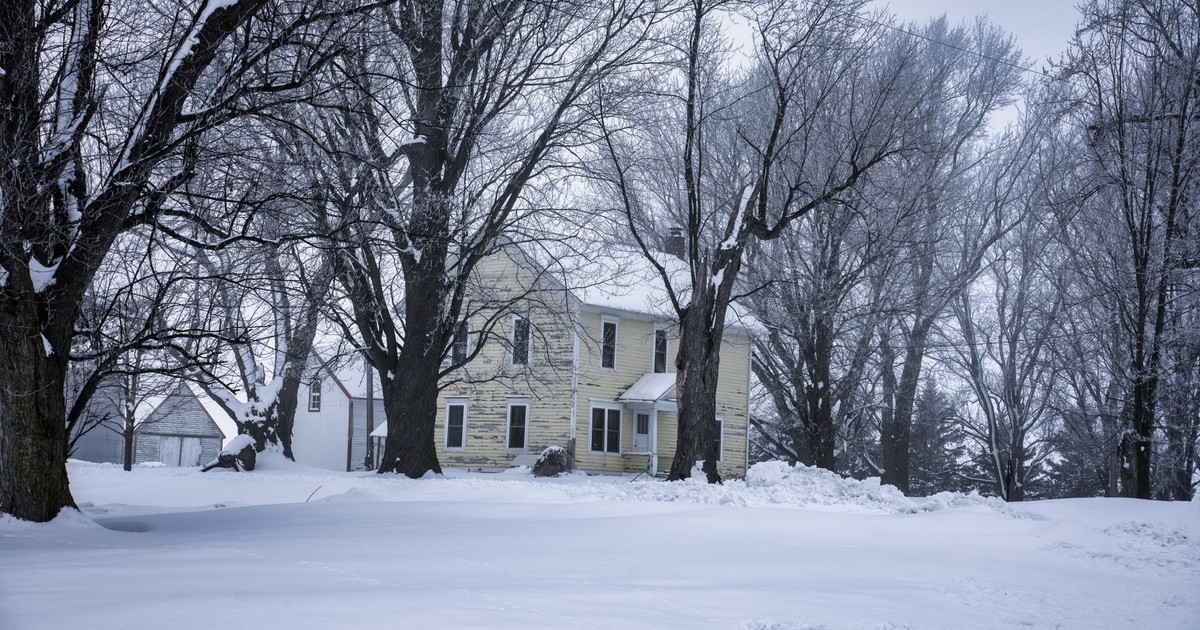A serene winter scene of a farmhouse surrounded by snow and trees in Minnesota, USA.