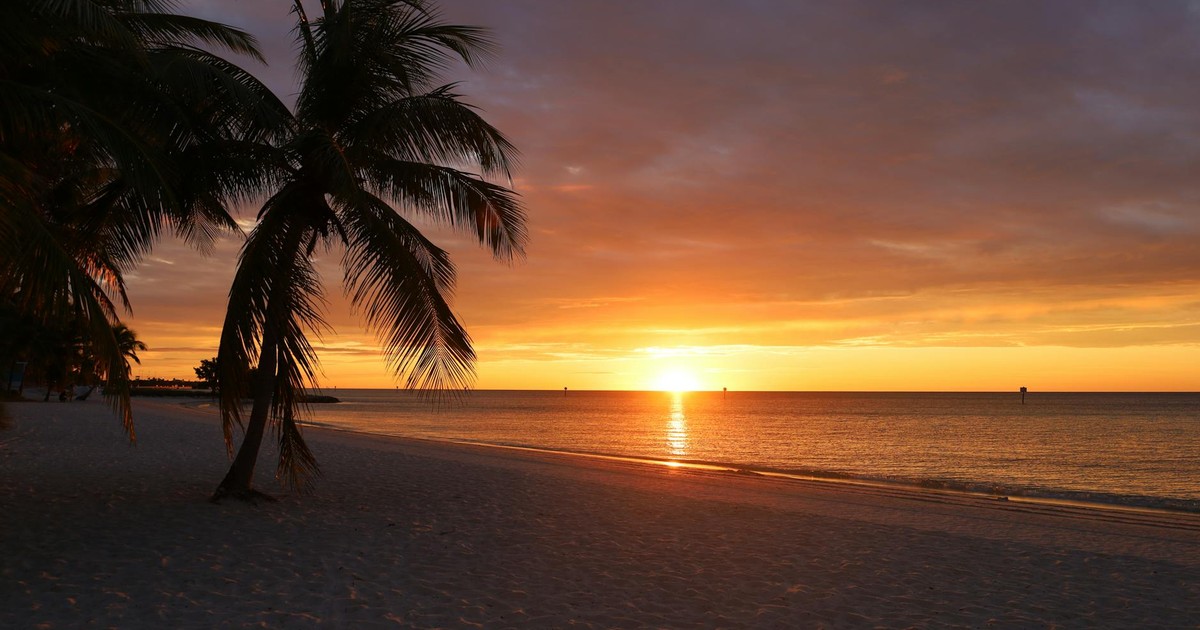 Experience a breathtaking sunset over the tranquil sea at a sandy beach in Key West.