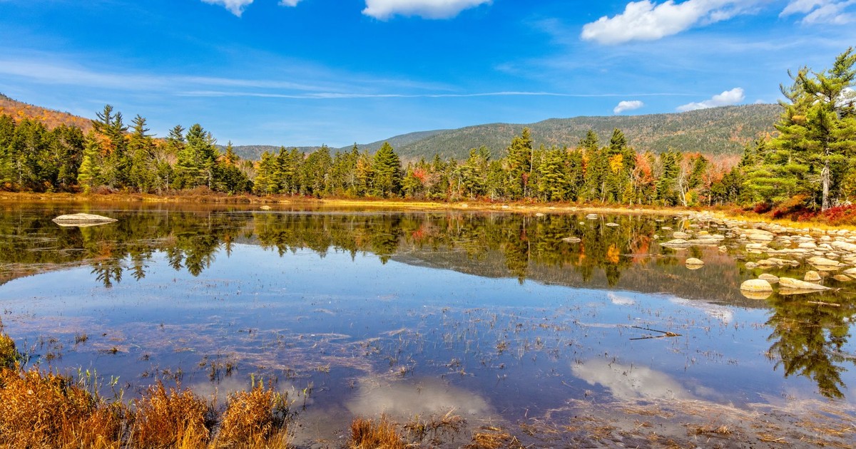 Beautiful autumn scenery of a calm lake in Lincoln, NH with vibrant fall foliage.