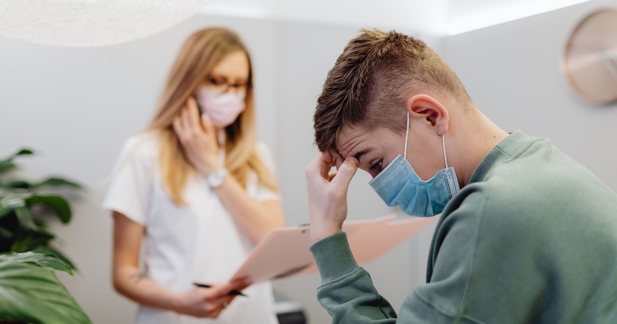 A worried patient discusses with a healthcare professional in a medical office setting.