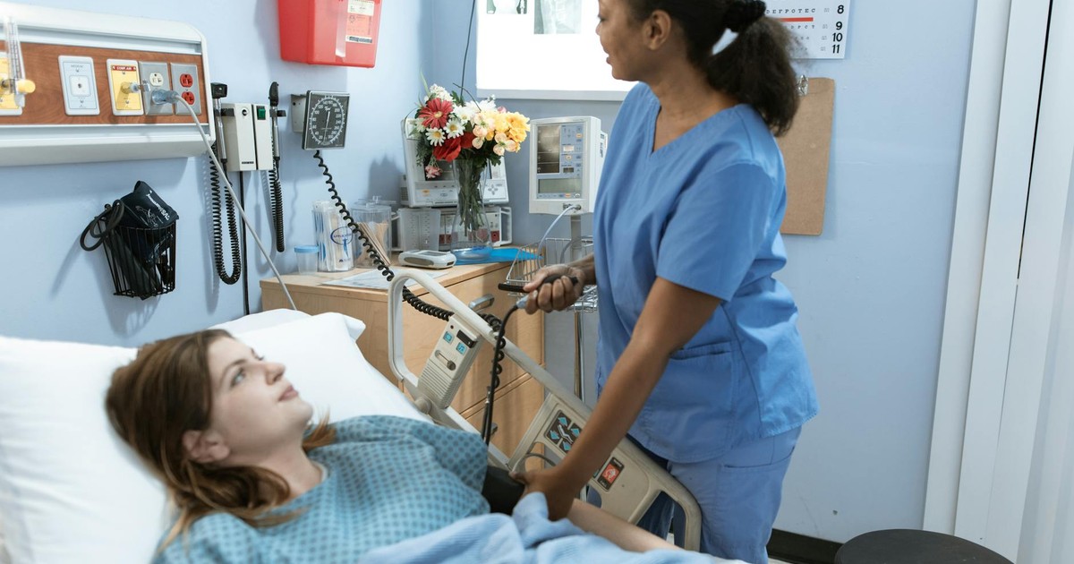 Nurse providing care to a patient in a hospital room with medical equipment.