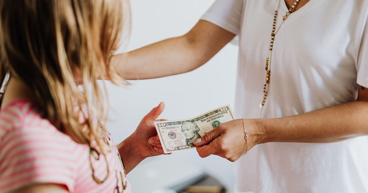 A woman handing money to a young girl, symbolizing family financial education and transactions.