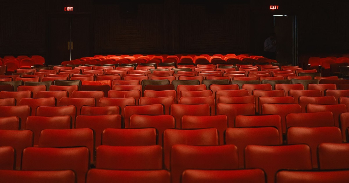 Rows of empty red seats inside a classic movie theater with a vintage ambiance.