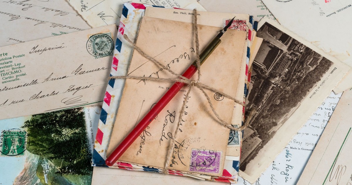 A collection of vintage postcards and envelopes tied with twine, featuring a pen and old stamps.