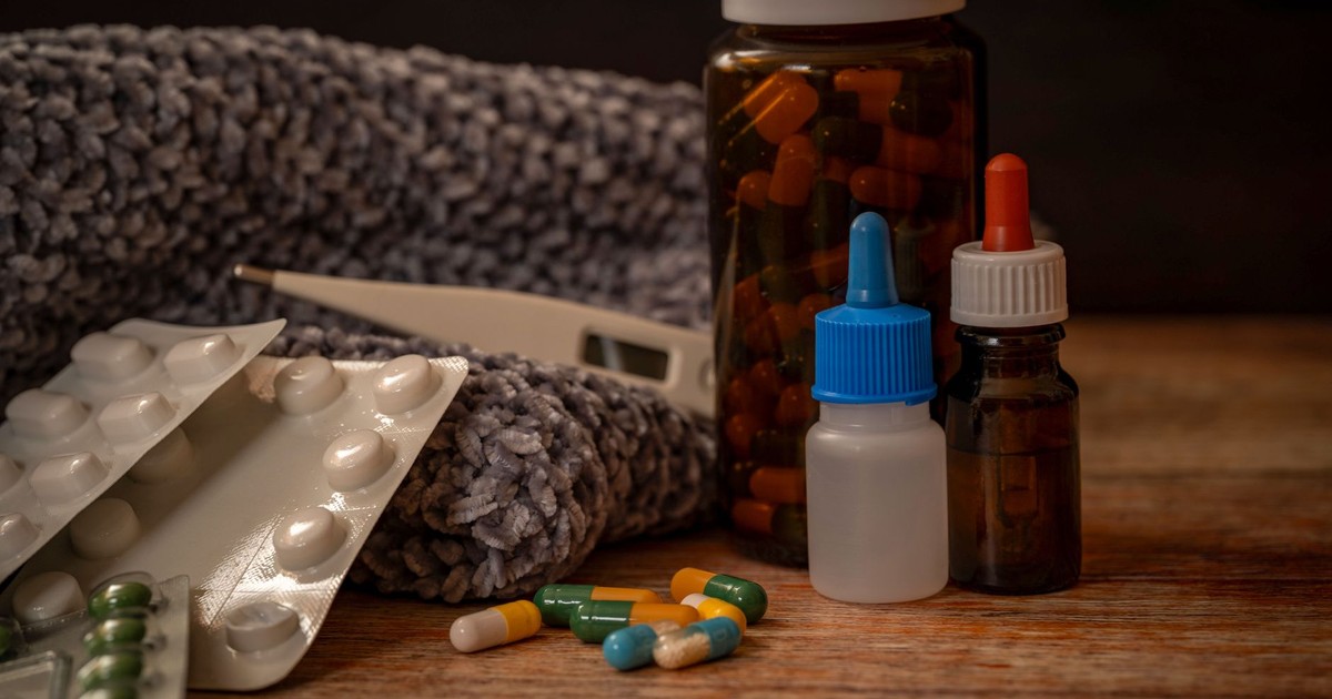 Collection of flu remedies including pills, thermometer, and scarf for winter cold relief.