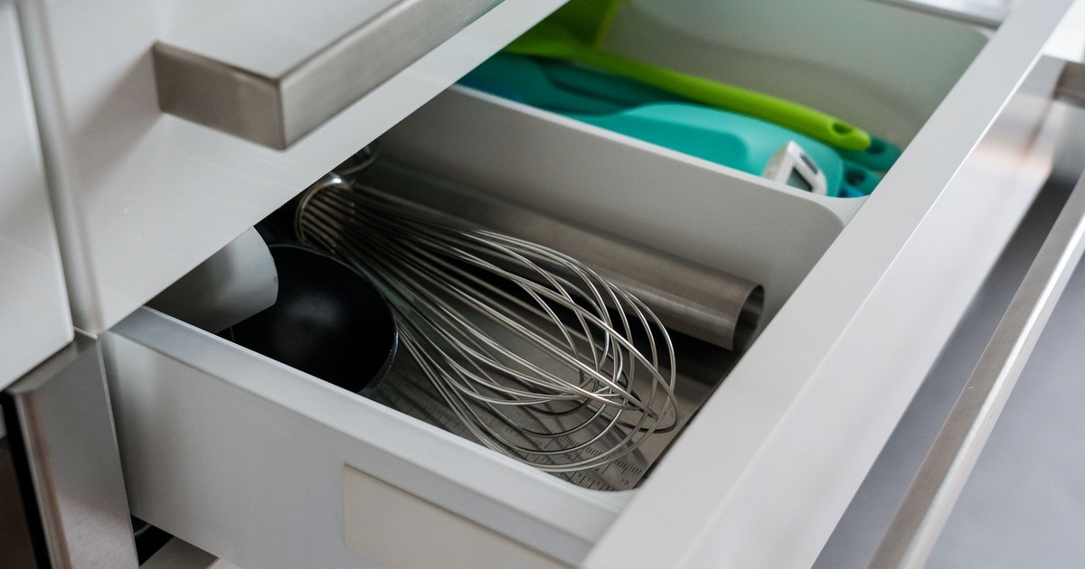 Open kitchen drawer showcasing organized utensils including a whisk and scoop.