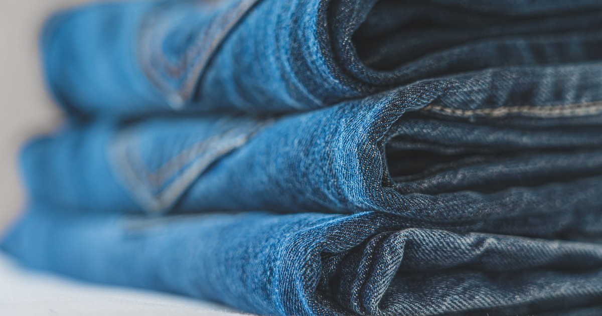 Detailed close-up image of a neat stack of blue folded denim jeans highlighting the fabric texture.