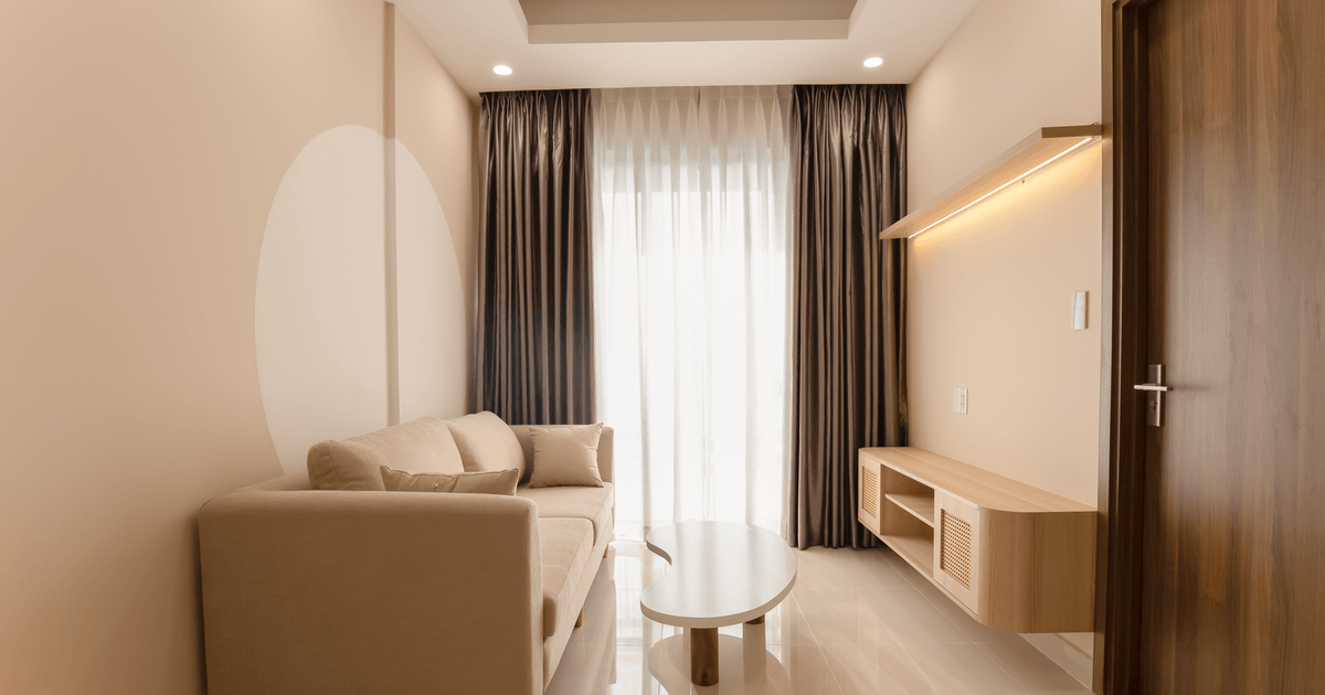 A minimalist living room with a beige sofa, modern table, and soft lighting.