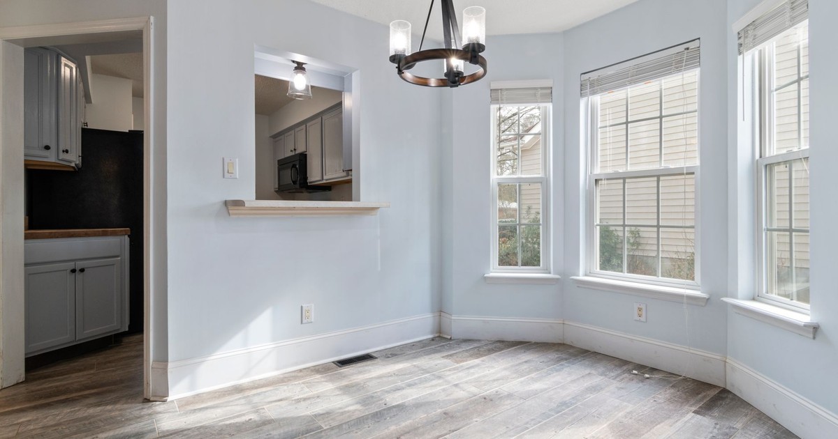 Sunlit empty room featuring a modern chandelier and wooden floors, ideal for home staging.