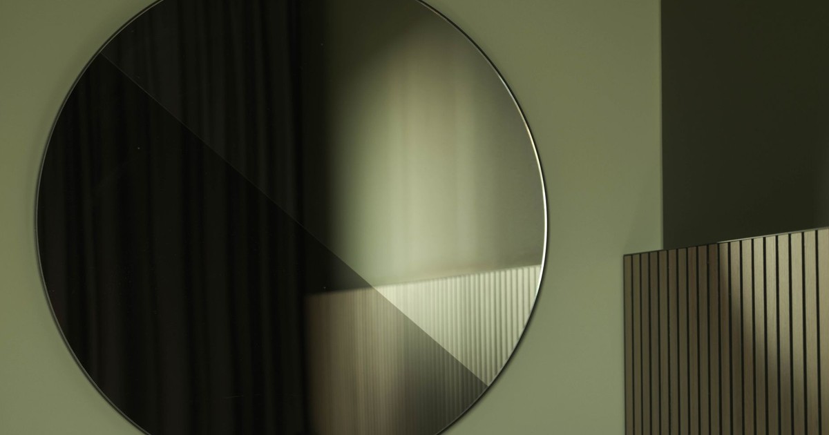 A large circular mirror reflecting soft light in a modern interior.