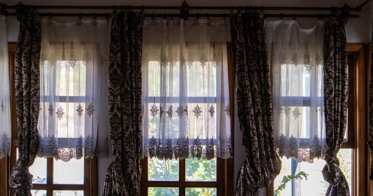 Sunlit room with elegant traditional curtains overlooking a garden view.