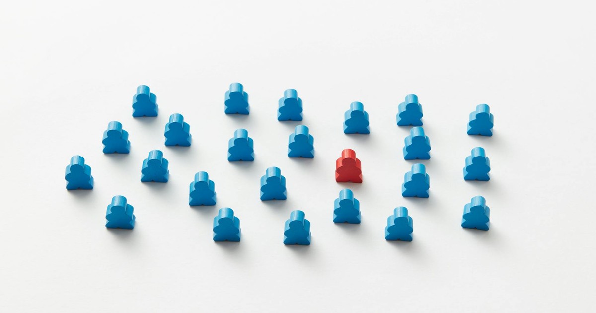 A red meeple stands out in a pattern of blue figures, symbolizing individuality.