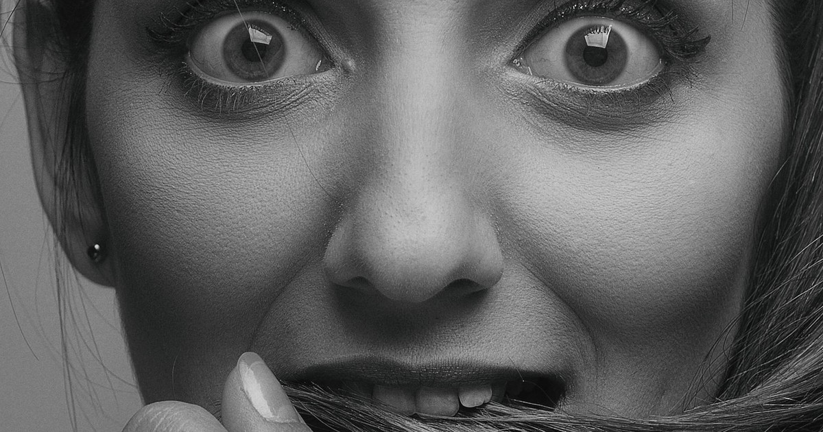 Expressive black and white close-up portrait depicting a worried woman holding her hair.