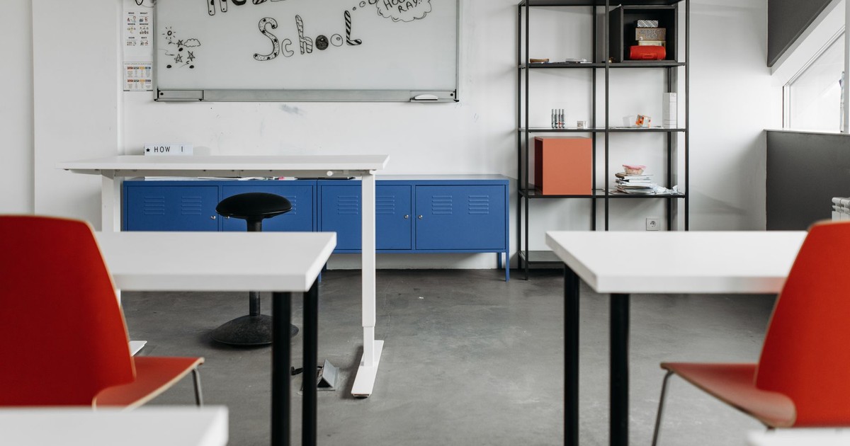 Empty classroom with modern desks, chairs, and whiteboard for educational settings.