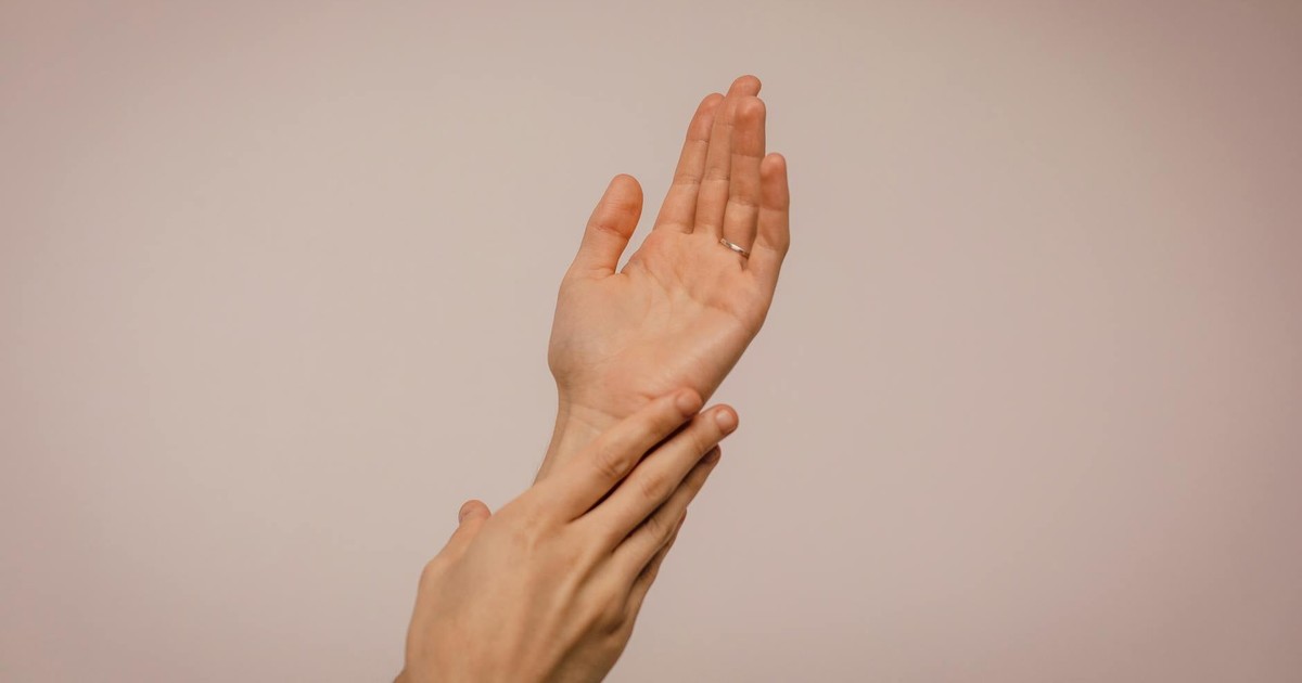 Close-up of hands gently caressing each other, symbolizing self-care and softness.