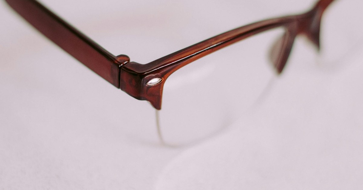 A detailed artistic close-up of a brown vintage style eyeglasses frame with a focus on the corner.