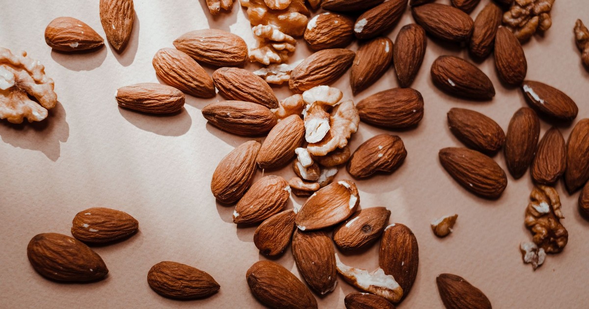 High-angle shot of almonds and walnuts scattered on a light backdrop, showcasing healthy snack options.