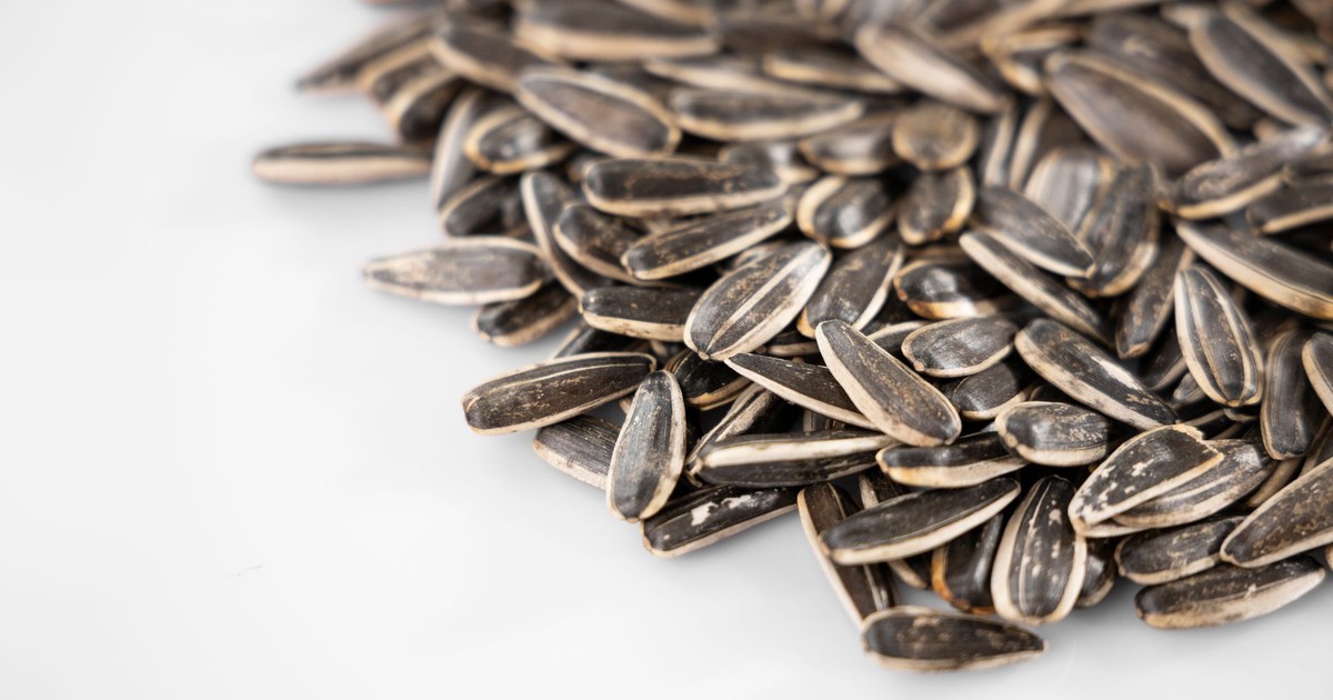 Pile of sunflower seeds displayed on a white surface, perfect for healthy snack themes.