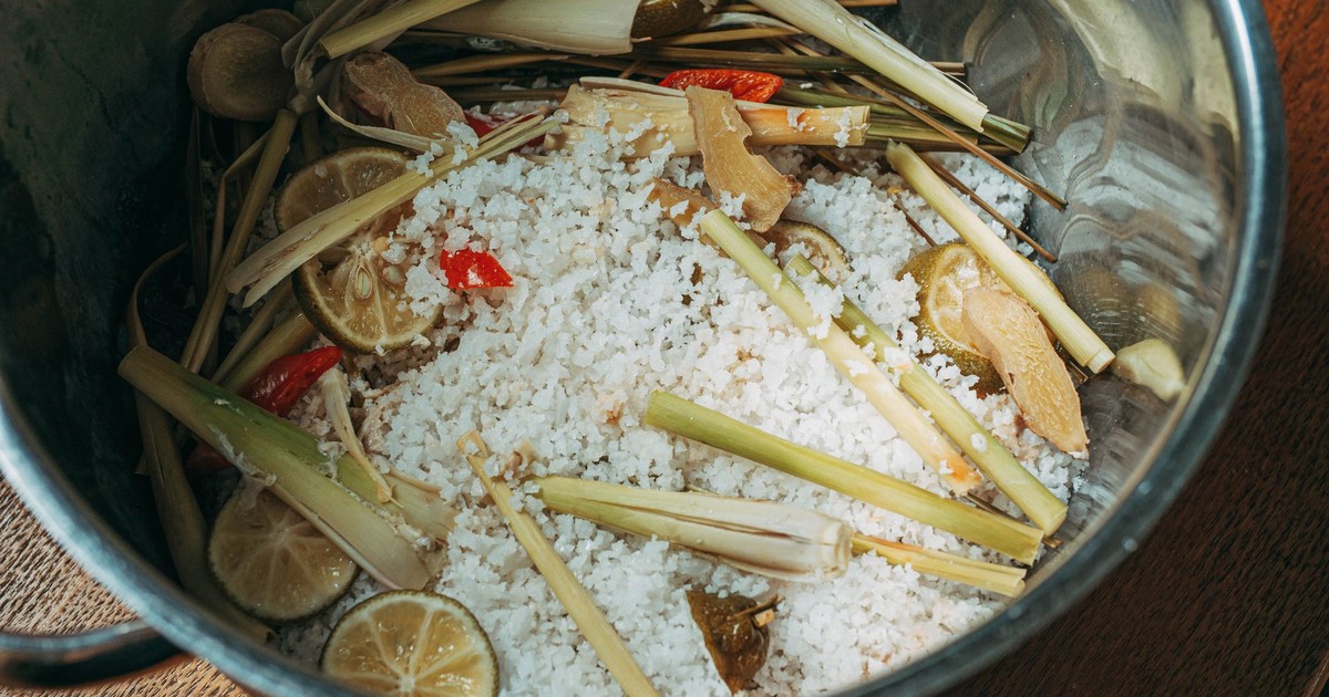 Top view of lemongrass, lime, ginger, and red chili with rice in a pot.