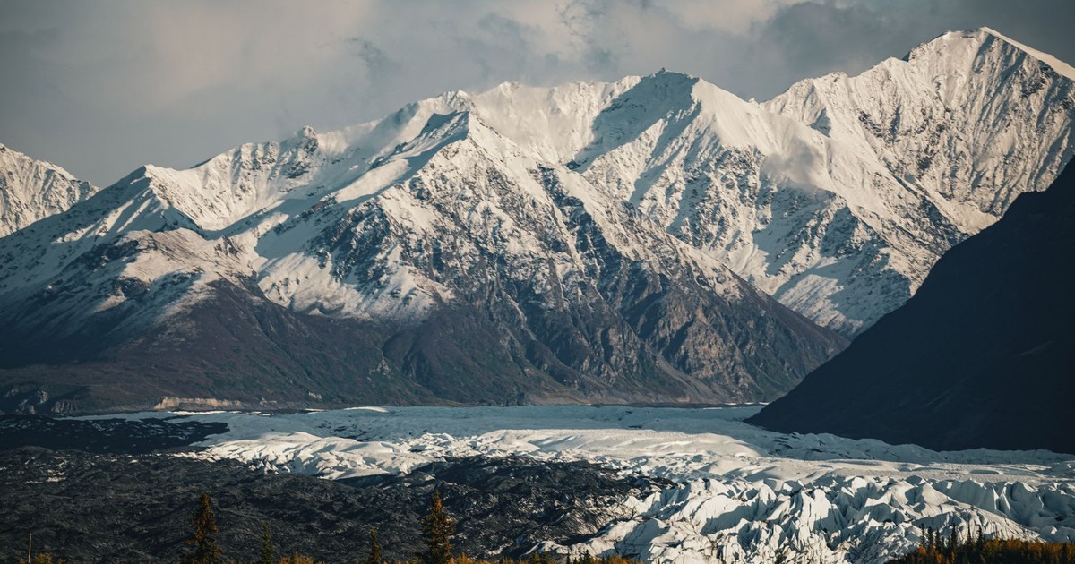 Breathtaking view of snow-capped mountains with a glacier below, captured in serene winter light.