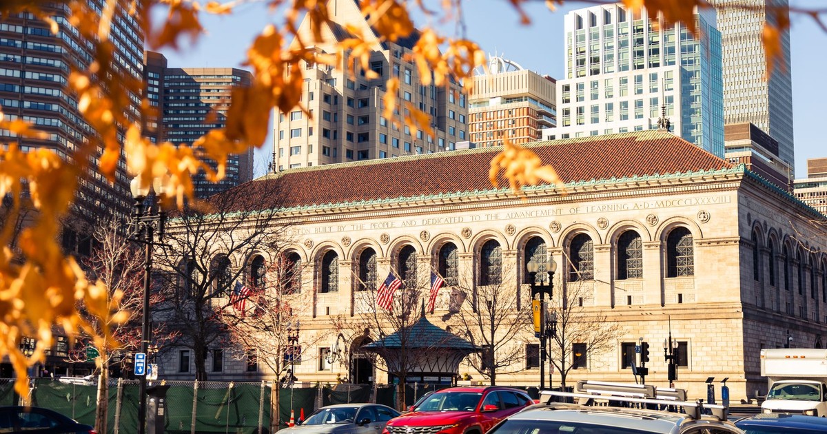 Historic Boston Public Library framed by autumn leaves in vibrant downtown cityscape.