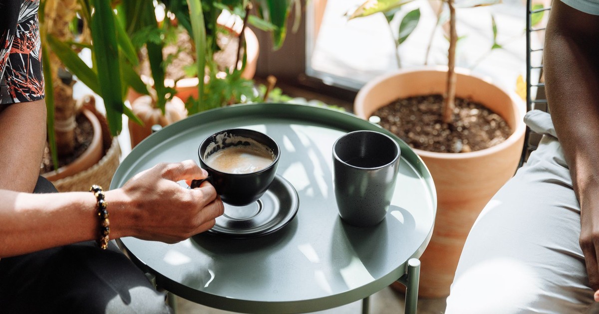 Cozy indoor setting with a coffee cup on a table amidst green plants.
