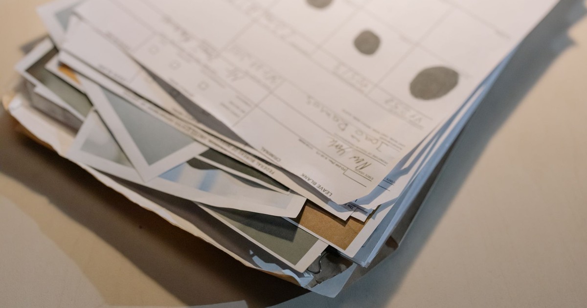 Close-up view of a stack of various papers and documents on a desk surface.