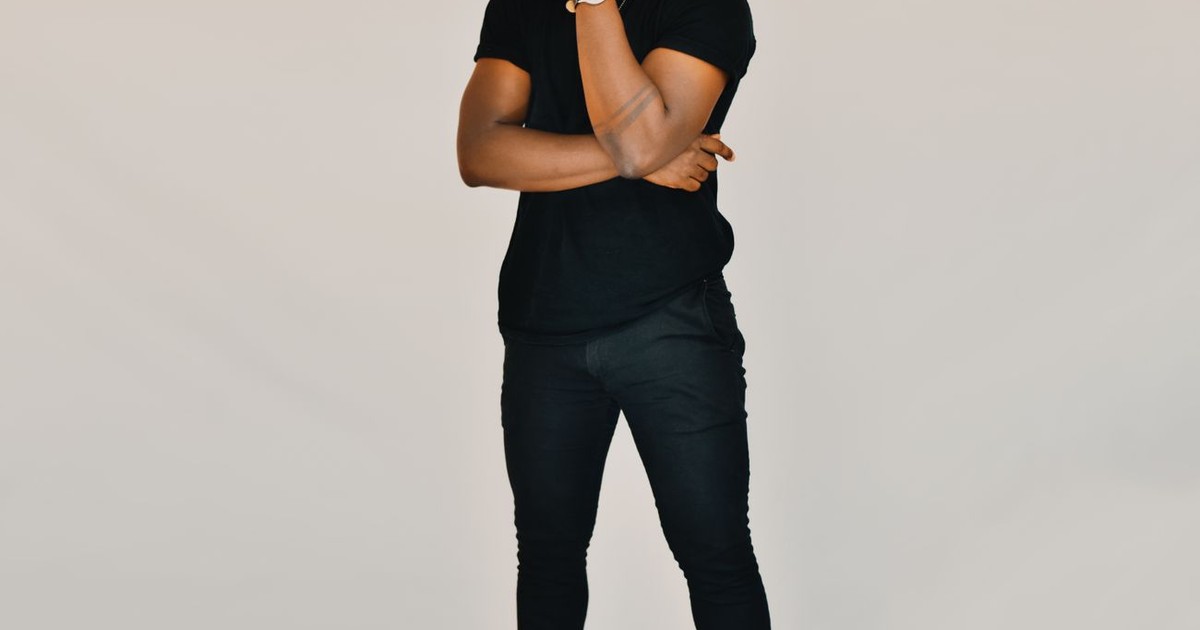 Stylish man with dreadlocks posing confidently in a studio setting with a white background.