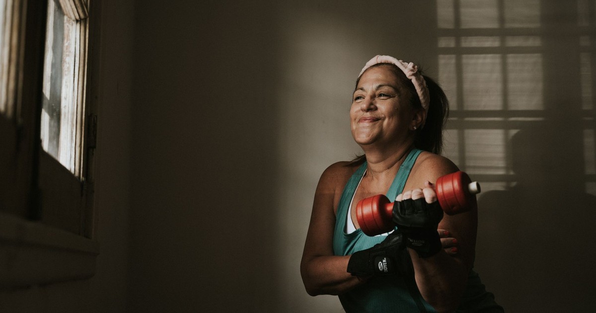 Confident middle-aged woman lifting dumbbells indoors, embracing a healthy lifestyle.