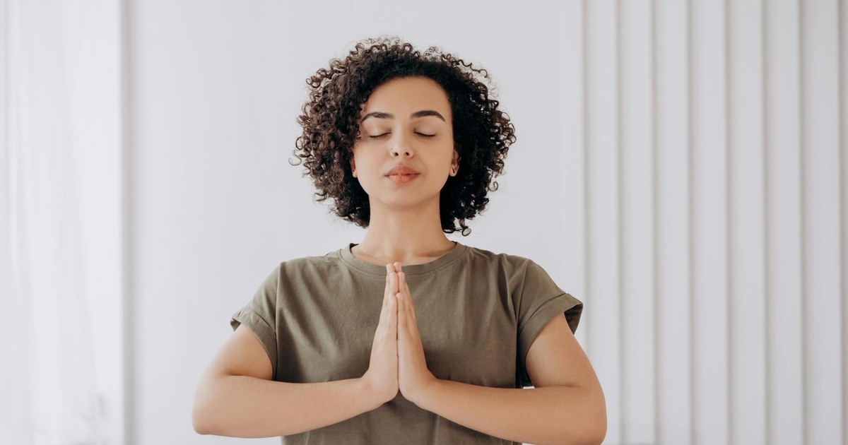 Young woman with curly hair meditates indoors, embracing tranquility and mindfulness.