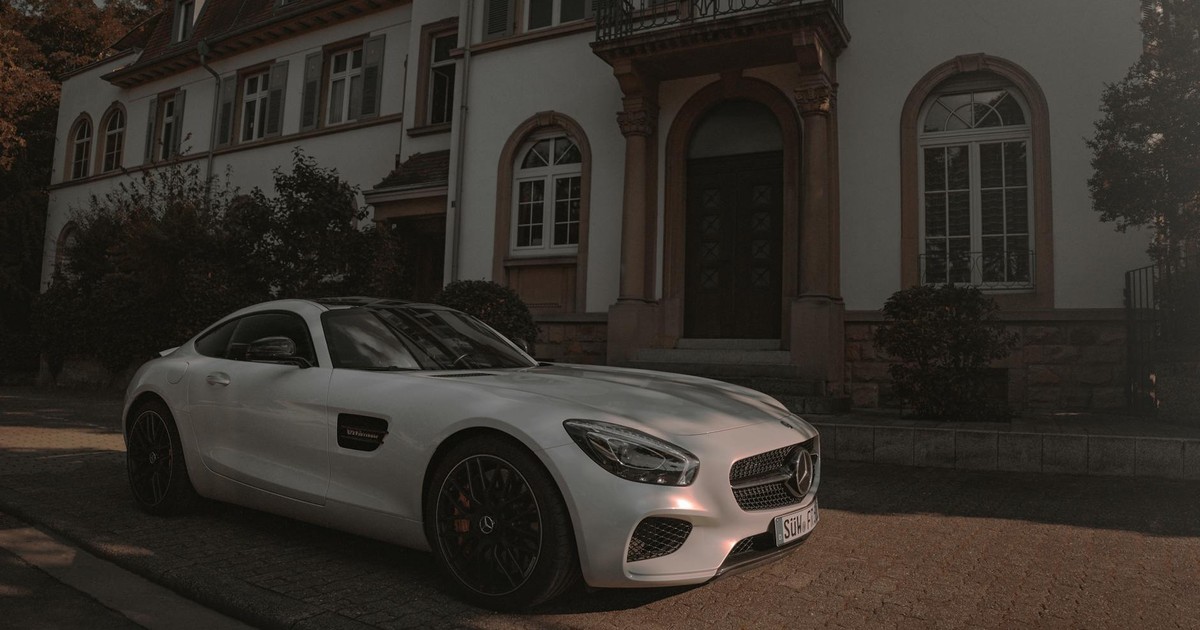 White luxury sports car parked outside a stylish residential home on a quiet street.