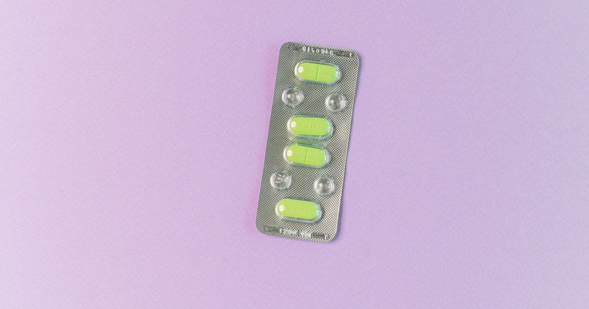 Top view of green tablets in a blister pack on a pastel purple background. Ideal for health and medication themes.