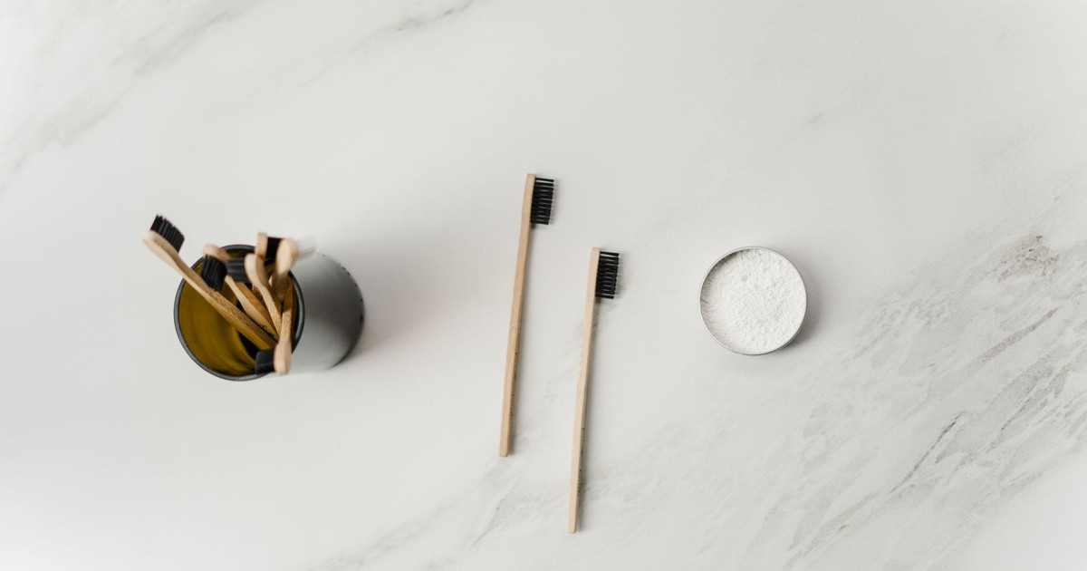 Flat lay of bamboo toothbrushes and powder, showcasing sustainable oral care tools on a marble surface.