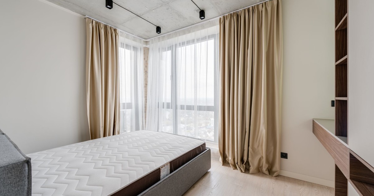 Spacious modern bedroom with cozy bedding and natural light.