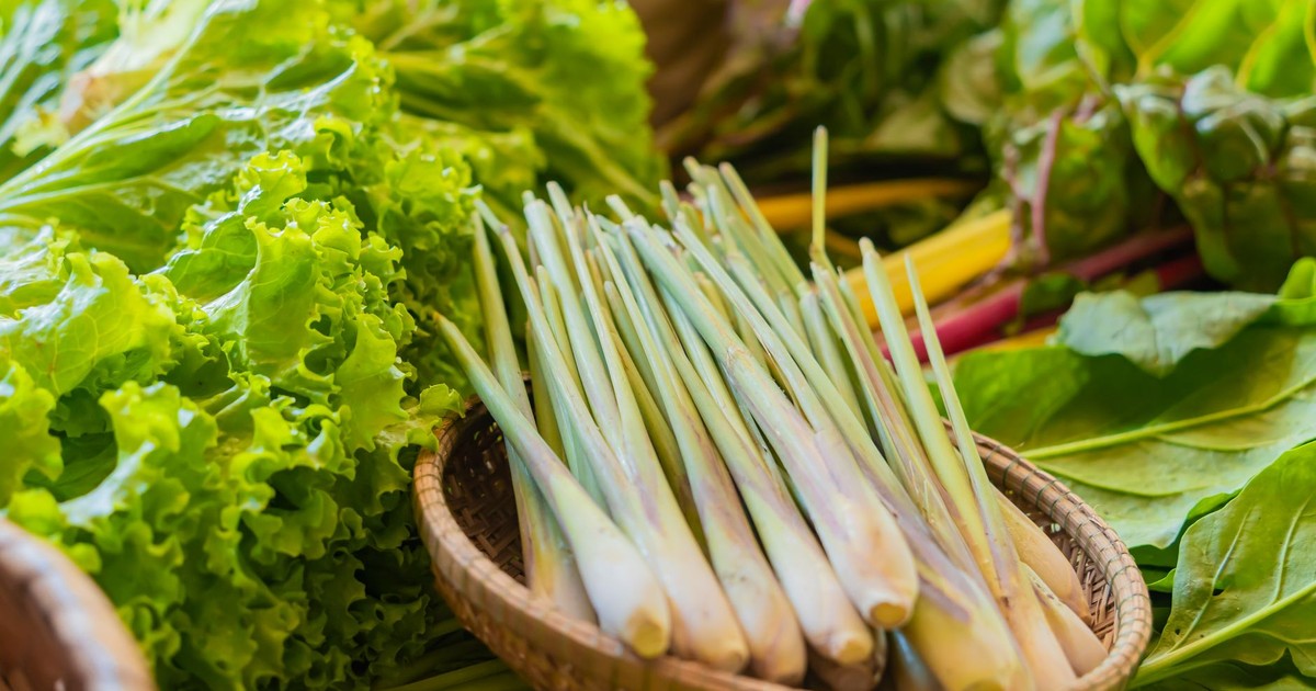 Close-up of fresh lemongrass and leafy vegetables on display at a vibrant local market.